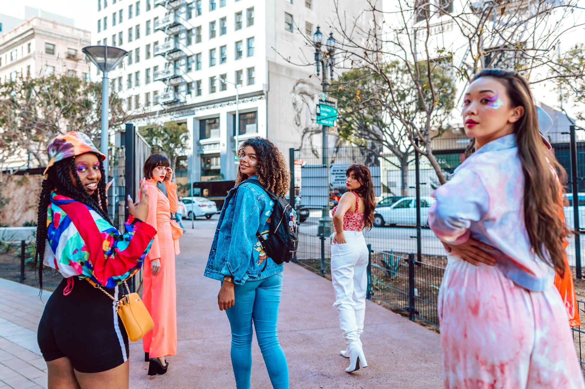 Diverse group of adults in colorful fashion posing on an urban street.