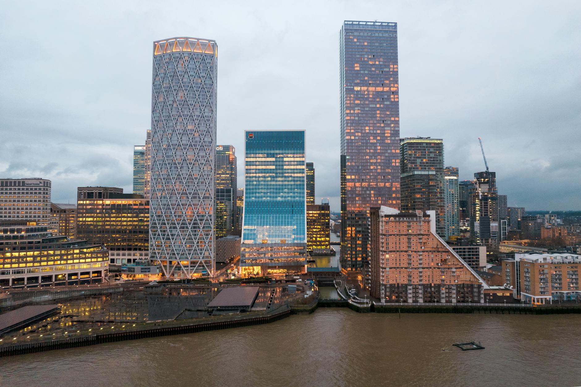 Stunning aerial view of Canary Wharf skyscrapers against a cloudy sky in London.