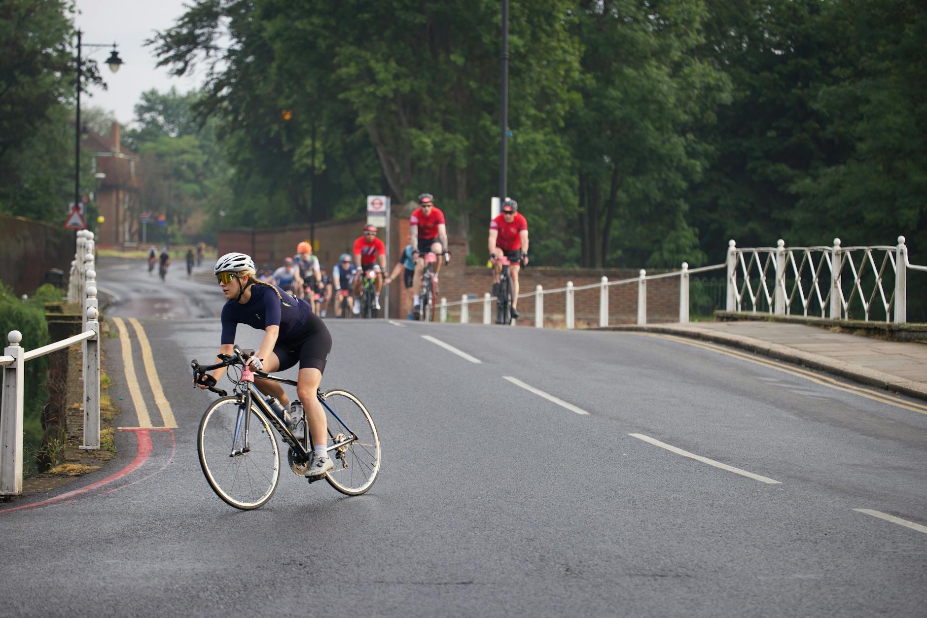 Group of cyclists engaged in a charity bike race on an urban road surrounded by greenery.